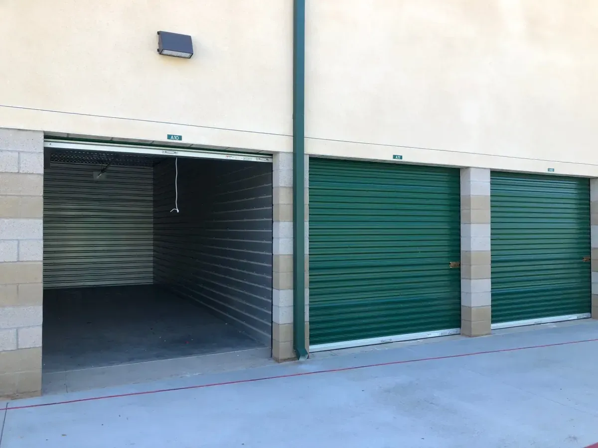Three green doored storage units with one open.