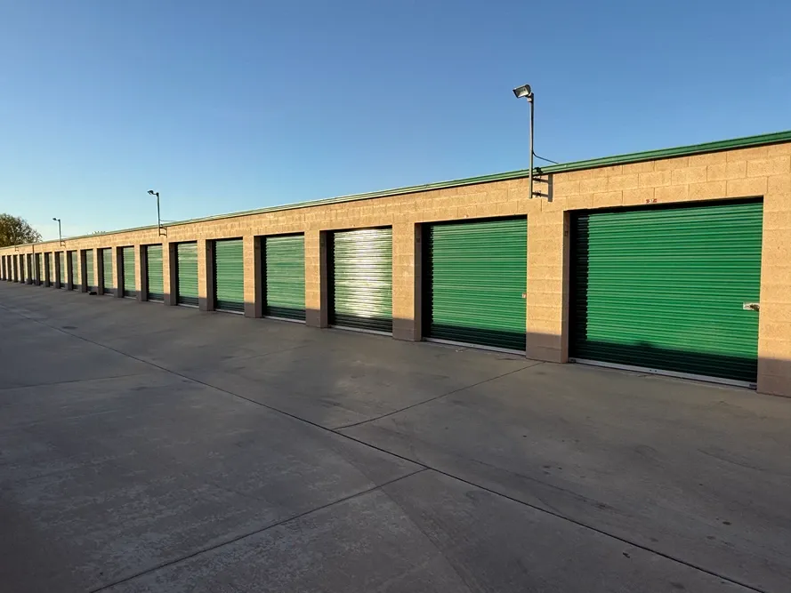 A row of green storage units at sunset.
